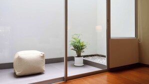 A corner of a room with a glass partition, a potted plant, and a white cushion. - w* | Spectacular 1BR w/ Terrace in Miraflores (Lima)