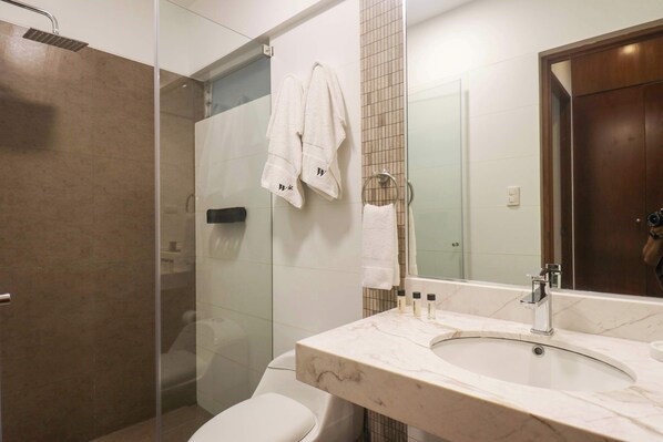 A modern bathroom with a glass-enclosed shower, a marble sink, and a toilet.