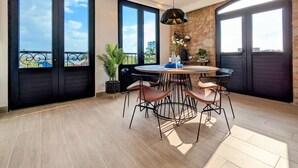 A spacious room with a round dining table, black chairs, and a hanging pendant light.