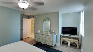 Una camera da letto con un letto, una cassettiera, una TV e una ventola a soffitto.
