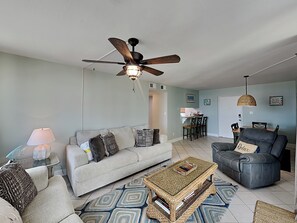 A living room with a ceiling fan, a sofa, a coffee table, and a chair.