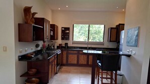 A modern kitchen with wooden cabinets, a black countertop, and a window providing natural light.