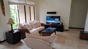 A living room with a sofa, a coffee table, a TV, and a lamp.