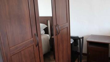 Una habitación con una cama, una mesita y un armario.