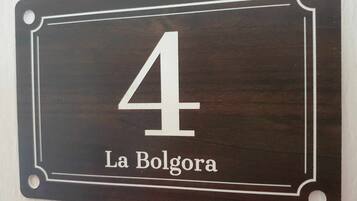 Uma placa de número de casa em madeira escura com o número 4 e o texto 'La Bolgora' abaixo.