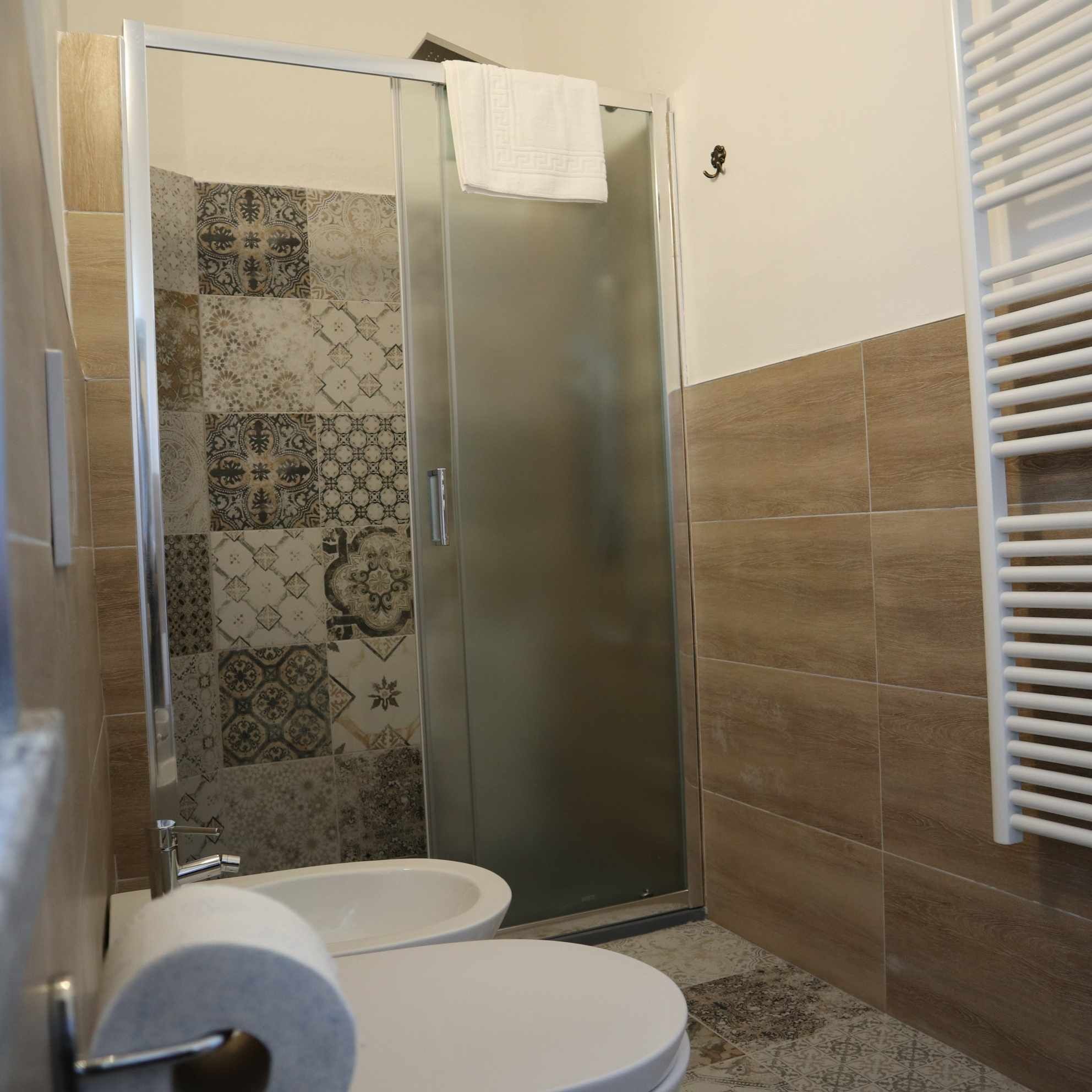 A bathroom with a shower enclosure, a toilet, and a towel rack.
