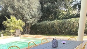 Un área de comedor al aire libre con una mesa rectangular y sillas amarillas, rodeada por un tapete azul estampado.