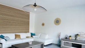 Un salón moderno con un sofá blanco, una mesa de centro oscura y un mueble para la televisión.