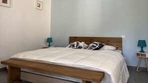 Une chambre à coucher avec un cadre de lit en bois, une literie blanche et deux tables de chevet avec des lampes.