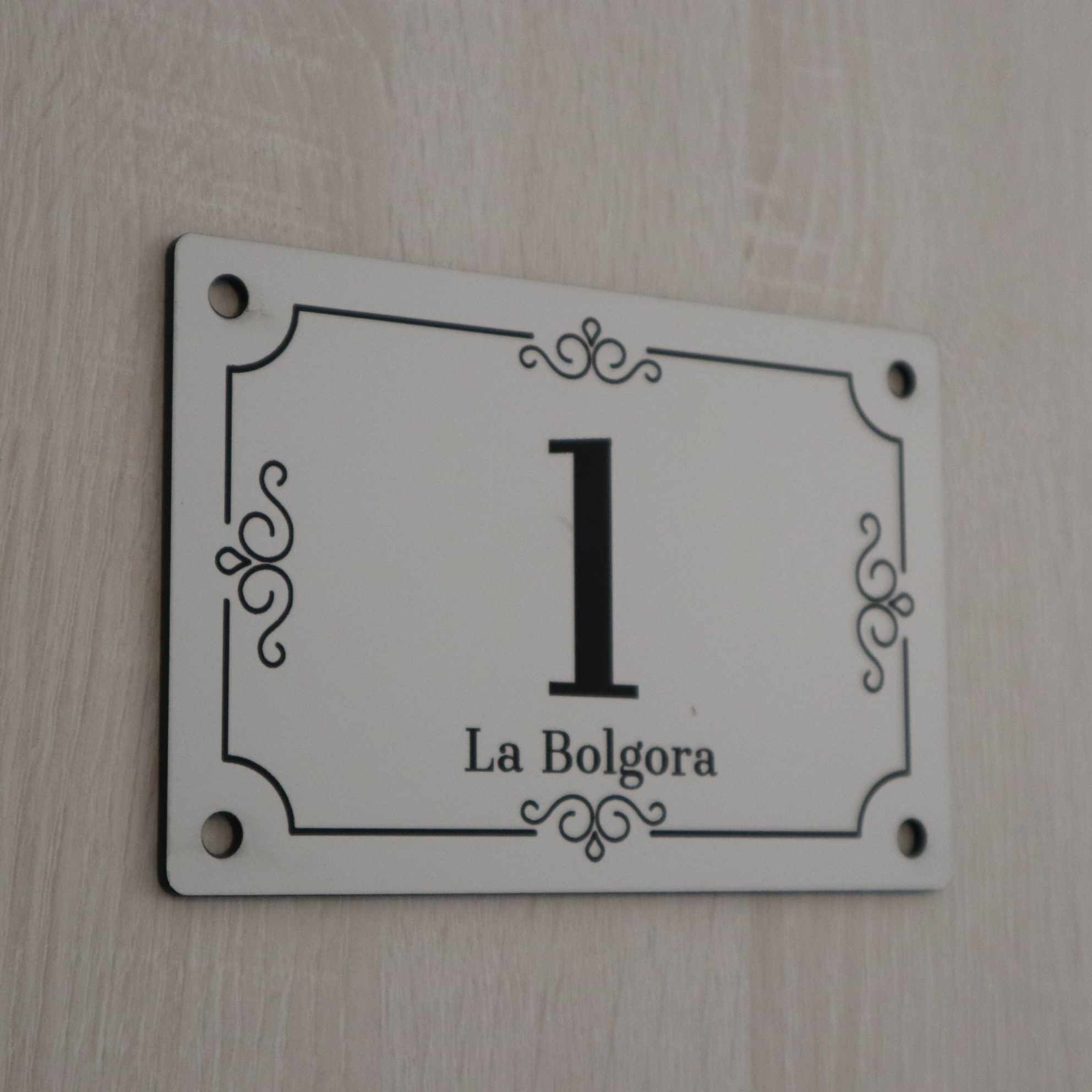 Een wit bord met een groot cijfer 1 en de tekst 'La Bolgora' op een muur.
