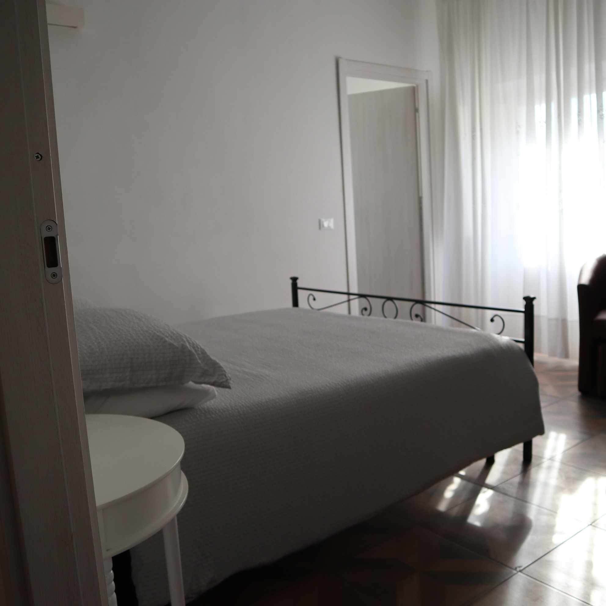 Un dormitorio con una cama, una mesa redonda y una puerta.