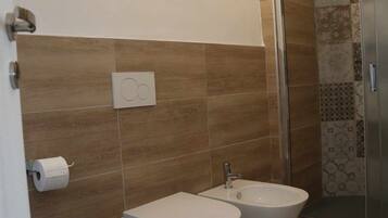 Un bagno con toilette, bidet e doccia.