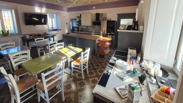 A kitchen with a dining area, equipped with a TV, a refrigerator, and a coffee machine. - Camera Deluxe (Recetto)