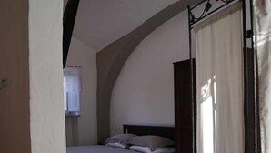 A bedroom with a bed, a window with a curtain, and a tiled floor. - Camera Deluxe (Recetto)