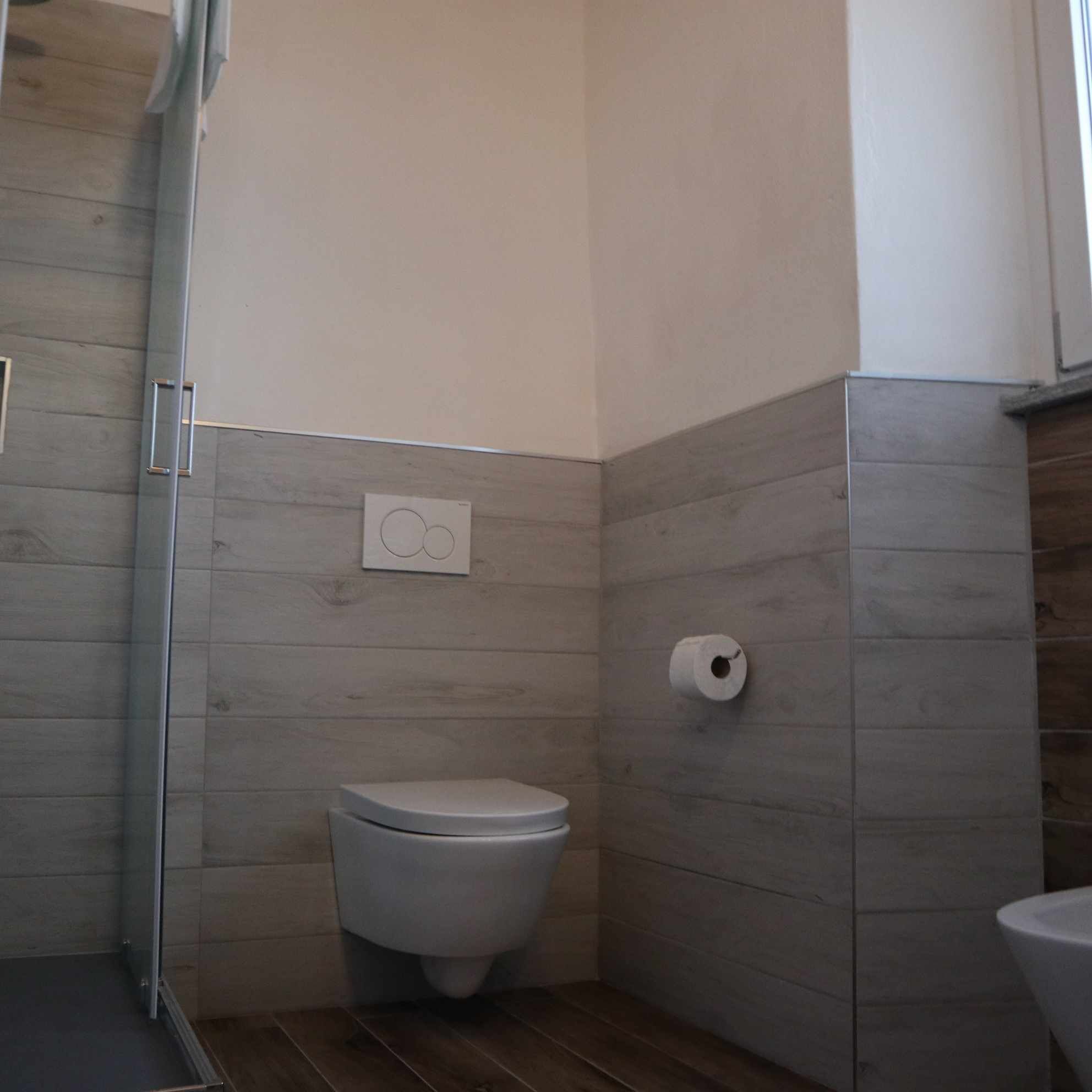 A small, modern bathroom with a toilet, a shower, and a towel rack.