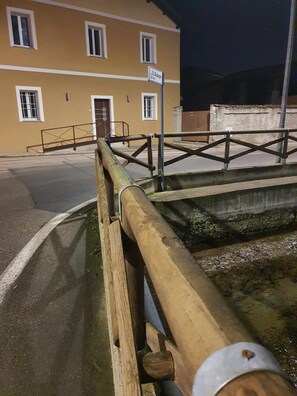 A street view with a yellow building, a metal structure, and a wooden beam. - Junior suite (Recetto)