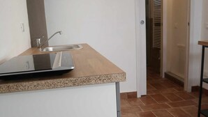 Une cuisine équipée d’un plan de travail, d’un évier et d’une porte donnant sur une autre pièce.