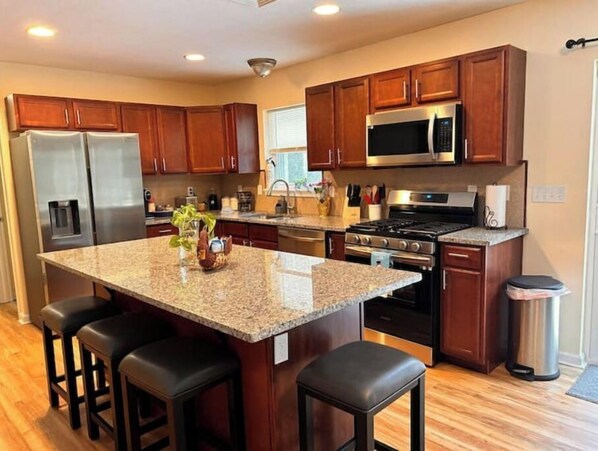A modern kitchen with granite countertops, stainless steel appliances, and wooden cabinets.