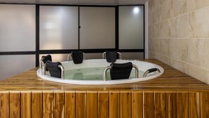 A circular hot tub with four chairs, set on a wooden platform, against a tiled wall with a black frame. - Loft, Historic Center, Bogotá (Bogotá)