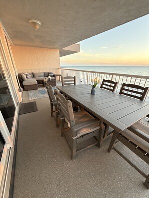 Un balcon avec une table à manger, des chaises et un canapé.
