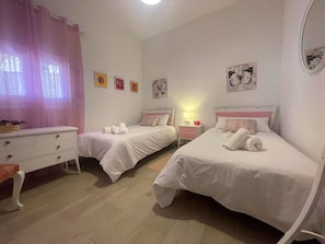 A bedroom with two beds, a dresser, and a nightstand with a lamp.