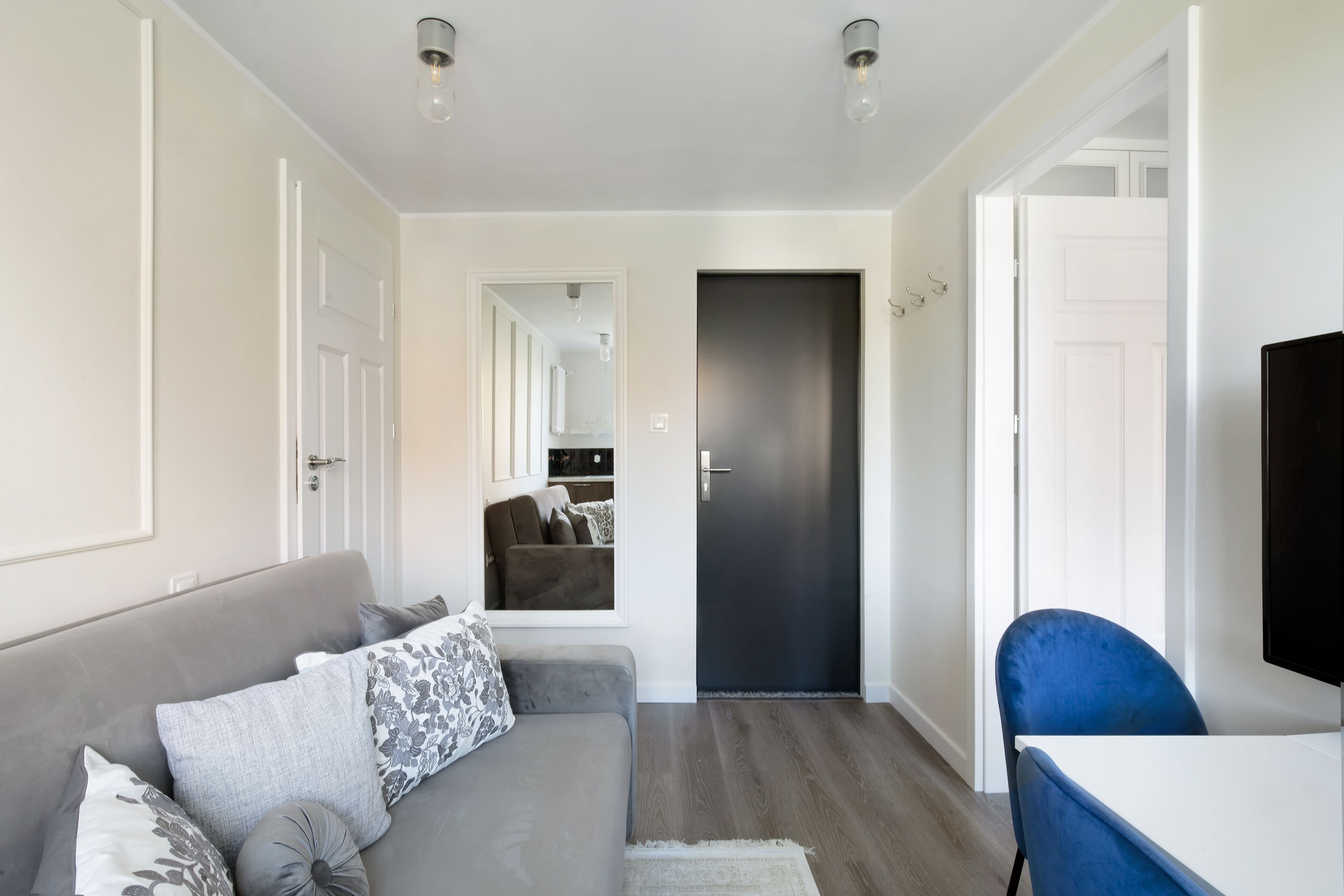 Een moderne woonkamer met een grijze bank, een blauwe fauteuil en een flatscreen televisie.