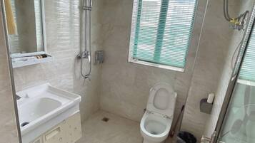 A small, compact bathroom with a toilet, sink, and shower.