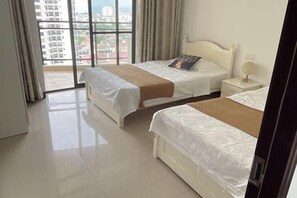 Un cuarto de hotel con dos camas, un ventanal grande y vistas a edificios.