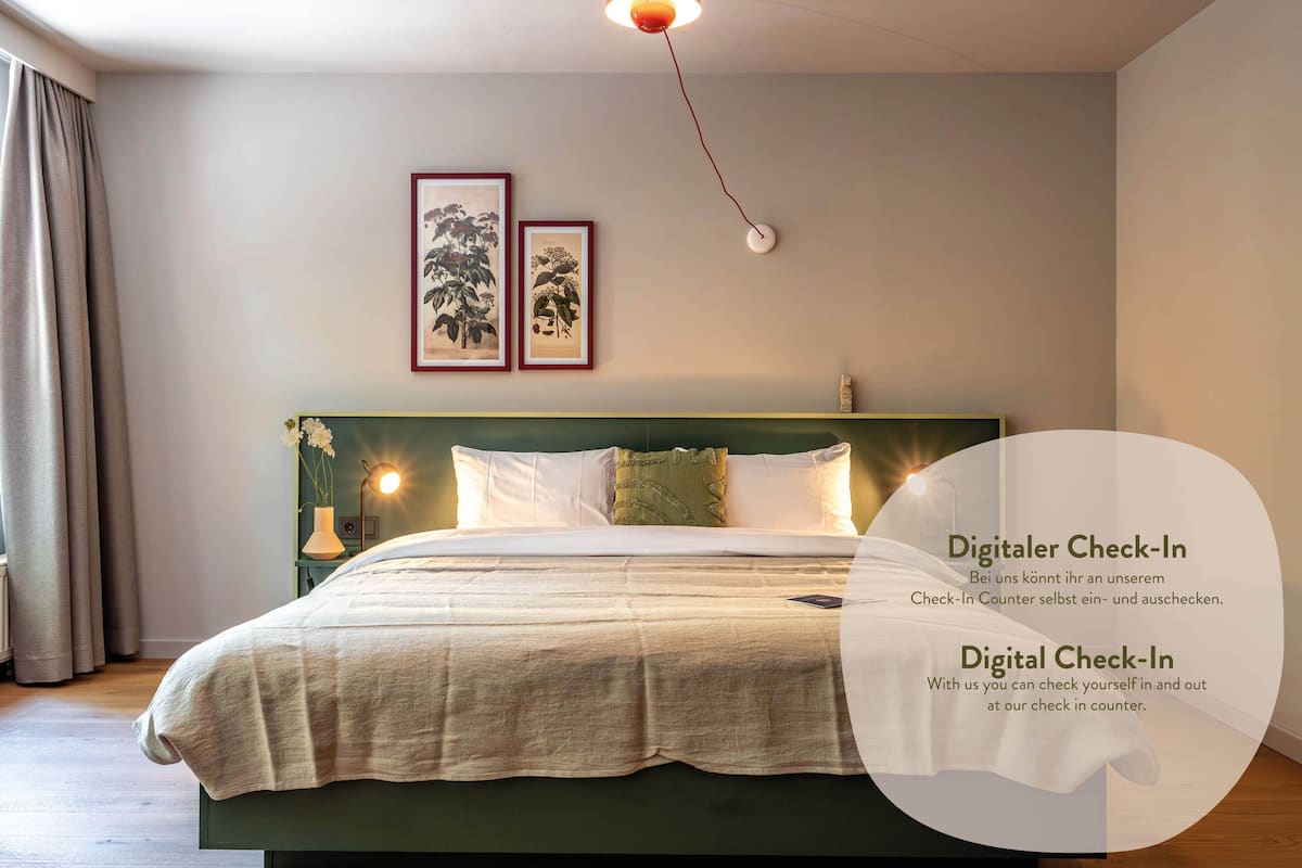 Una habitación de hotel con una cama, una mesita de noche, una lámpara y dos cuadros en la pared.