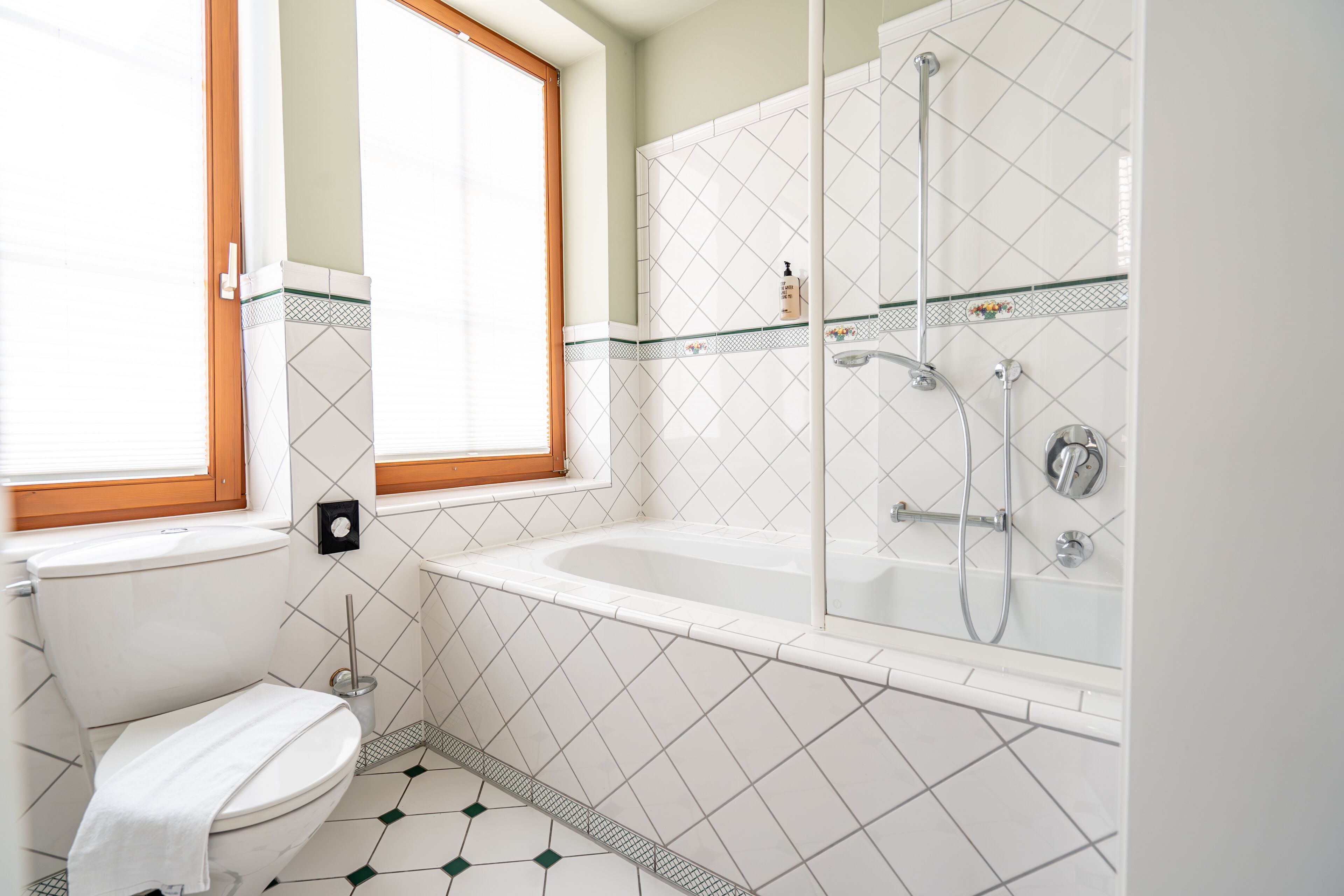 A bathroom with a toilet, a window, a bathtub, and a shower.