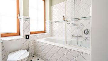 A bathroom with a toilet, a window, a bathtub, and a shower.
