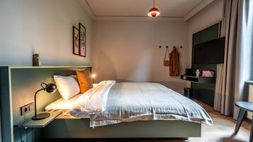 A modern bedroom with a bed, bedside table, lamp, and a TV on a stand.