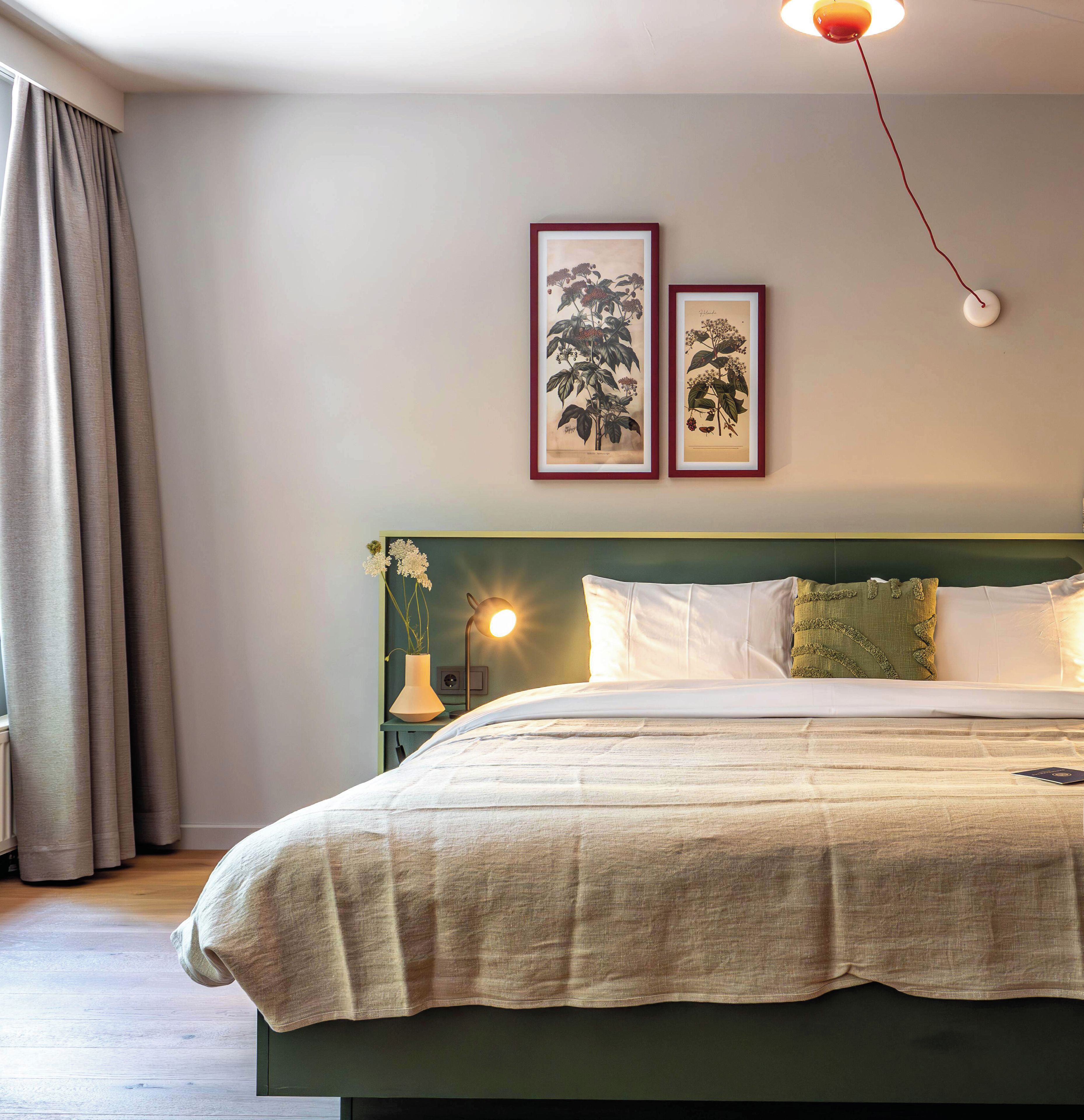 Een hotelkamer met een bed, een nachtkastje, een lamp en twee ingelijste foto's aan de muur.