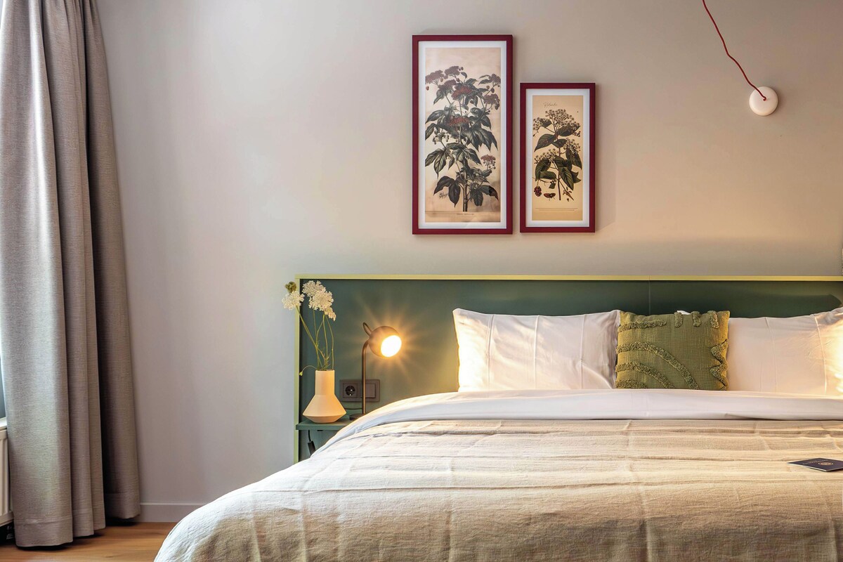 Une chambre d’hôtel avec un lit, une table de chevet, une lampe et deux tableaux encadrés au mur.