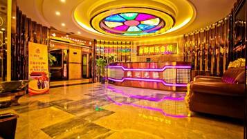 A hotel lobby with a reception desk, a seating area, and a decorative ceiling.