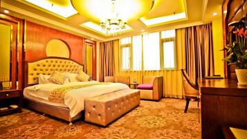A hotel room with a large bed, a desk, and a chair.