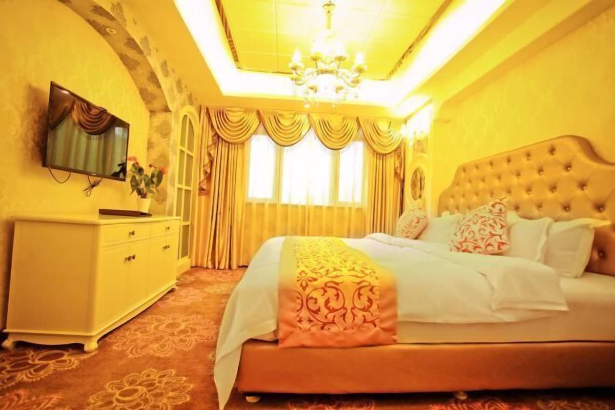 Un dormitorio con cama, cómoda, televisor y candelabro.