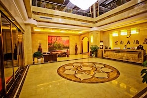 Vestíbulo de hotel con una recepción, un diseño de piso decorativo y un techo alto con tragaluces.