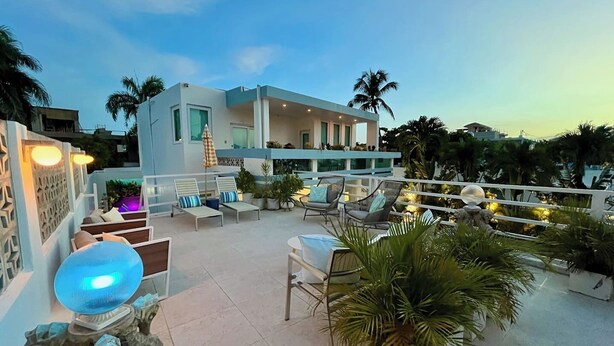 A rooftop terrace with lounge chairs, a decorative sculpture, and a modern building in the background.