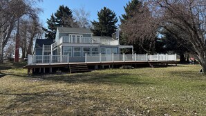 A two-story house with a deck and a covered porch. - Cottage on the Lake (American Falls)