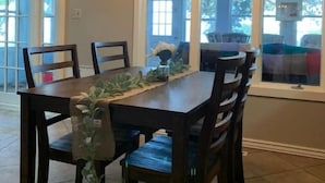 A dining area with a wooden table and chairs, a glass-top table, and a hanging light fixture. - Cottage on the Lake (American Falls)