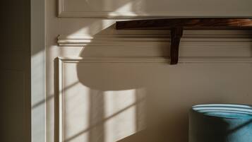A room with a white wall, a wooden shelf, and a rolled-up blue mat on the floor.