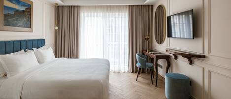 Habitación de hotel con una cama grande, un escritorio con silla, un televisor y un cuadro en la pared.