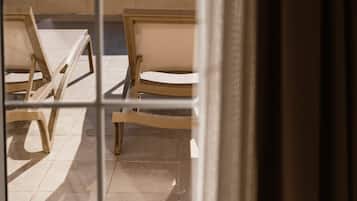 A view through a window of a room with a tiled floor and several wooden chairs.