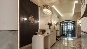 A reception desk with a laptop, a chandelier, and a wall-mounted sign. - Palazzo Castagna (Ghaxaq)