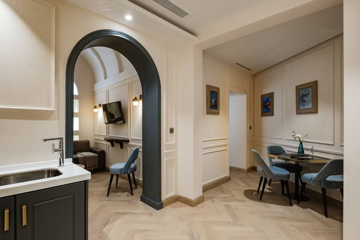 A modern kitchen with a built-in sink, a dining area with a table and chairs, and a hallway with framed artwork.