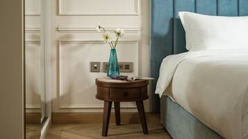 A bedroom with a bed, a nightstand, a vase with flowers, and a wall socket.