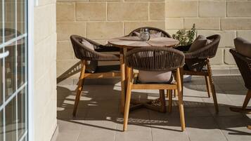 Un patio al aire libre con una mesa redonda de madera y seis sillas de mimbre, cada una con un cojín.