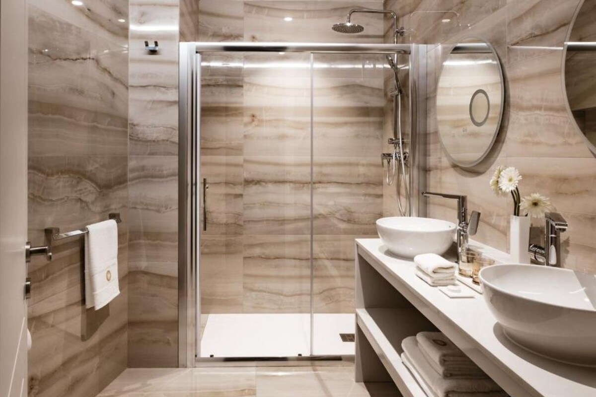 A modern bathroom with a glass-enclosed shower, two sinks, and a large mirror.