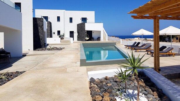 A modern resort with a swimming pool, lounge chairs, and a view of the sea. - Luxury hospitality, outstanding view (Thira - Santorini)